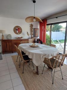 a dining room with a white table and chairs at Plaisirs de Lège in Lège-Cap-Ferret