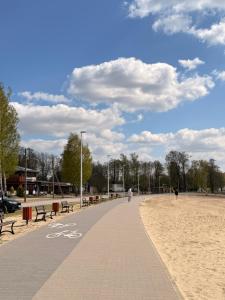 a bike path next to a beach with benches at Domki nad Firlejem in Firlej