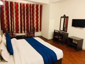 a bedroom with a bed and a television and curtains at Kalinga Intercontinental By Maa Vaishno Hotels India Pvt Ltd in Manāli +18 photos