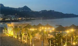 a beach with tables and umbrellas at night at Ludovica's house 2 in Giardini Naxos