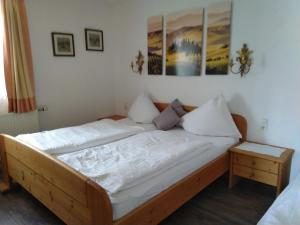 a bedroom with a wooden bed with white sheets and pillows at Haus Orleander in Rehgraben