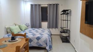 a small room with a bed and a table and a window at Studio prático e tranquilo em Jacobina in Jacobina