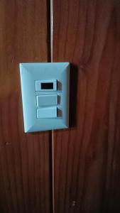 a white lightswitch on a wooden wall at Hospedaje Martita Patagonia in Coihaique