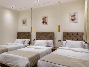 three beds in a room with white walls at Shiny Pyramids Boutique Hotel in Cairo