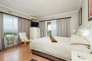 a bedroom with a large bed and a desk and window at FlowithLin Guesthouse in Durban +22 photos