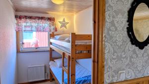 a bunk bed room with two bunk beds and a mirror at Rolig häst, Kaneeling Stugby AB in Dalskog