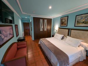 a bedroom with a large bed and a red chair at Hotel Boutique El Pescador in Cudillero +30 photos