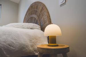 a lamp on a table next to a bed at Gîte de La Sulpicière - avec clim in Cholet