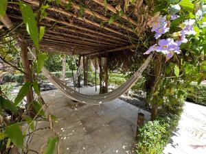 a hammock in a pergola with flowers at Oasis Tropical in Paracuru
