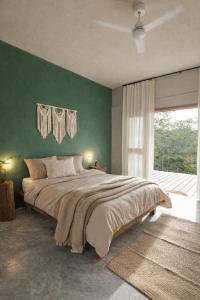 a bedroom with a large bed with a green wall at Selva Morena in Felipe Carrillo Puerto