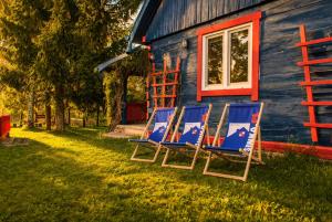 three chairs sitting in the grass in front of a house at Agroturystyka Husinka pl in Husinka