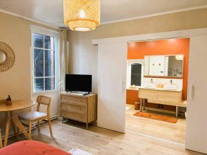 a bathroom with a television and a sink and a desk at Le cottage du Breil in Verfeil