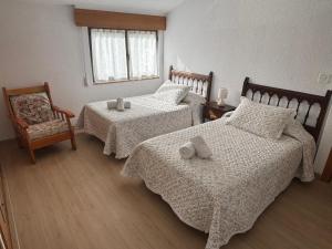 a bedroom with two beds and a chair and a window at Casa cerca de Las Medulas in Puente de Domingo Flórez