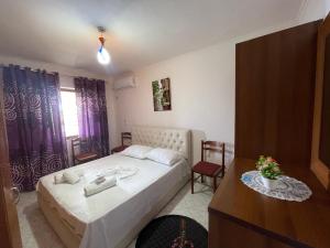 a bedroom with a large white bed and a table at Summerland Lukovë in Sarandë