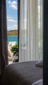 a bedroom with a window with a view of the ocean at Hotel Porta Ksamil in Ksamil +75 photos