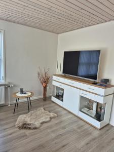 a living room with a flat screen tv and a table at Annes Hus in Rødekro