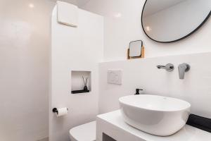 a white bathroom with a sink and a mirror at Kalami in Kokkari +36 photos