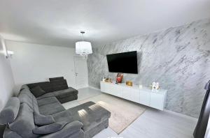 a living room with a couch and a tv on a wall at Apartament ICAS 2 in Dej