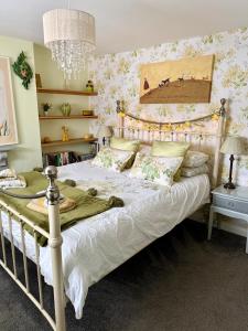 a bedroom with a large white bed with flowers on the wall at Oligrae Cottage in Bridport
