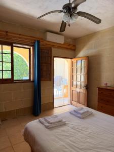 a bedroom with a bed with a ceiling fan and a window at Stella & Stone Guesthouse in Għarb