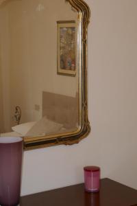 a mirror hanging on a wall next to a bed at Villa Iliana in Lucca