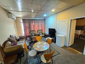 a living room with a couch and a table and chairs at HERSH Palace Hotel in Erbil