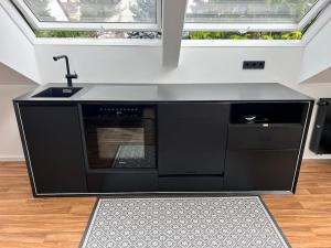 a black kitchen with a sink and a stove at Modern Attic Loft in Weisenheim am Sand