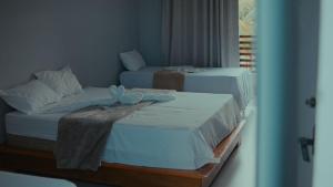 two beds in a room next to a window at Estância Costa do Sol in Nova Viçosa