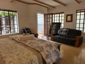a bedroom with a bed and a couch and windows at Deco Cottage in Centurion