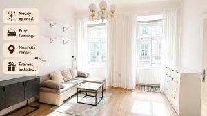 a white living room with a couch and a chandelier at City Center Apartment in Brno