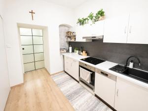 a kitchen with white cabinets and a wooden floor at City Center Apartment in Brno