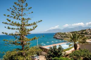 a pine tree next to a body of water at Poppy Villas in Agios Nikolaos