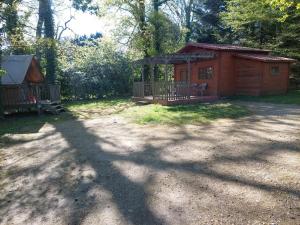 a small wooden cabin with a porch in the woods at Chalet l'écureuil in Treigny +1 photo