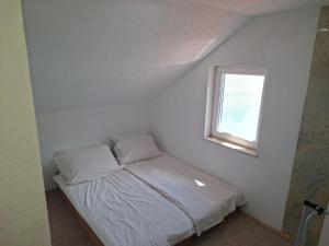 ein kleines Bett in einem weißen Zimmer mit einem Fenster in der Unterkunft Edison in Jablanica