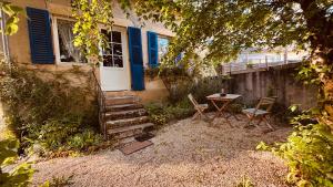 a house with blue doors and a table and chairs at La Maison du Rosier in Saint-Honoré-les-Bains