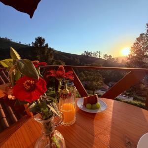 a table with a vase of flowers and a plate of fruit at Chalé Sonho Diniz 3 in Monte Verde
