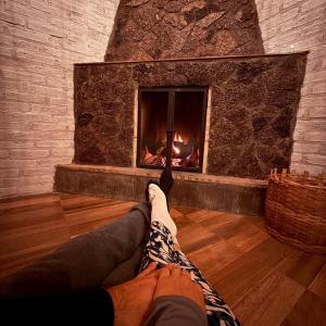 a person laying on the floor in front of a fireplace at Chalé Sonho Diniz 3 in Monte Verde