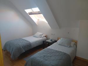 two beds in a attic room with a window at Ático en Ribeira Ría de Arousa in Ribeira