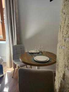 a wooden table with plates and wine glasses on it at Charming cozy nest - old town in Annecy