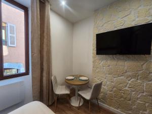 a room with a table and a tv on a stone wall at Charming cozy nest - old town in Annecy