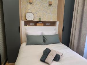 a bed with two pillows and a clock on a wall at Charming cozy nest - old town in Annecy
