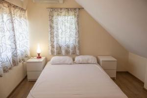 a bedroom with a white bed and a window at Вила Карапча in Stoyan Zaimovo
