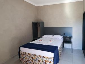 a bedroom with a bed with a blue and white blanket at Hotel Pousadas Club Smart in Sorocaba