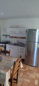 a kitchen with a table and a stainless steel refrigerator at Cabaña Dos Pinos in Durazno +3 photos