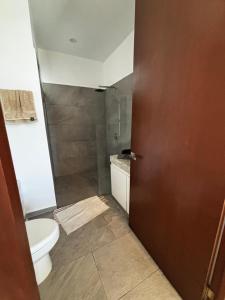 a bathroom with a toilet and a glass shower at Departamentos Nütuuk in Mérida