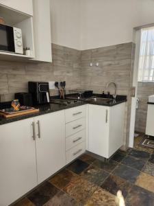 a kitchen with white cabinets and a sink at The Studios on Smuts in Ermelo