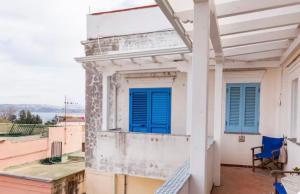 a balcony with blue shutters on a building at Maison Artista in Procida