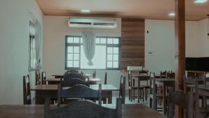 a dining room with tables and chairs and a window at Estância Costa do Sol in Nova Viçosa