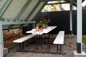 a picnic table with two benches and flowers on it at KB House apartman in Malý Horeš