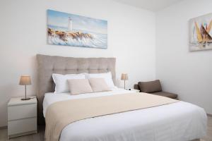 a bedroom with a large white bed and a chair at Apartments Dadic with parking & playground in Medulin